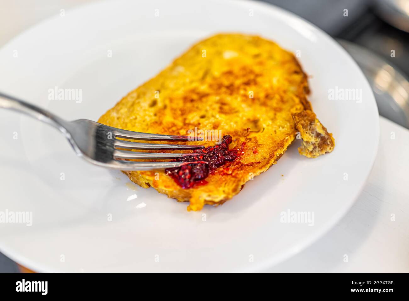 Pain de brioche à la challah cuit maison pain grillé français servi sur une assiette blanche avec fourchette et confiture de framboise sucrée Banque D'Images