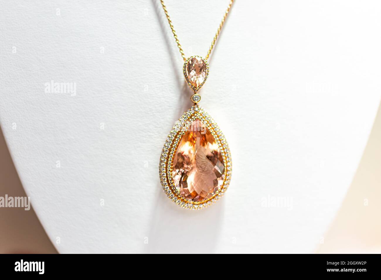 Collier de rose doré en pierre précieuse pêche en forme ovale avec petites pierres de diamant pierres précieuses sur chevalet de vente au détail avec backgro blanc Banque D'Images