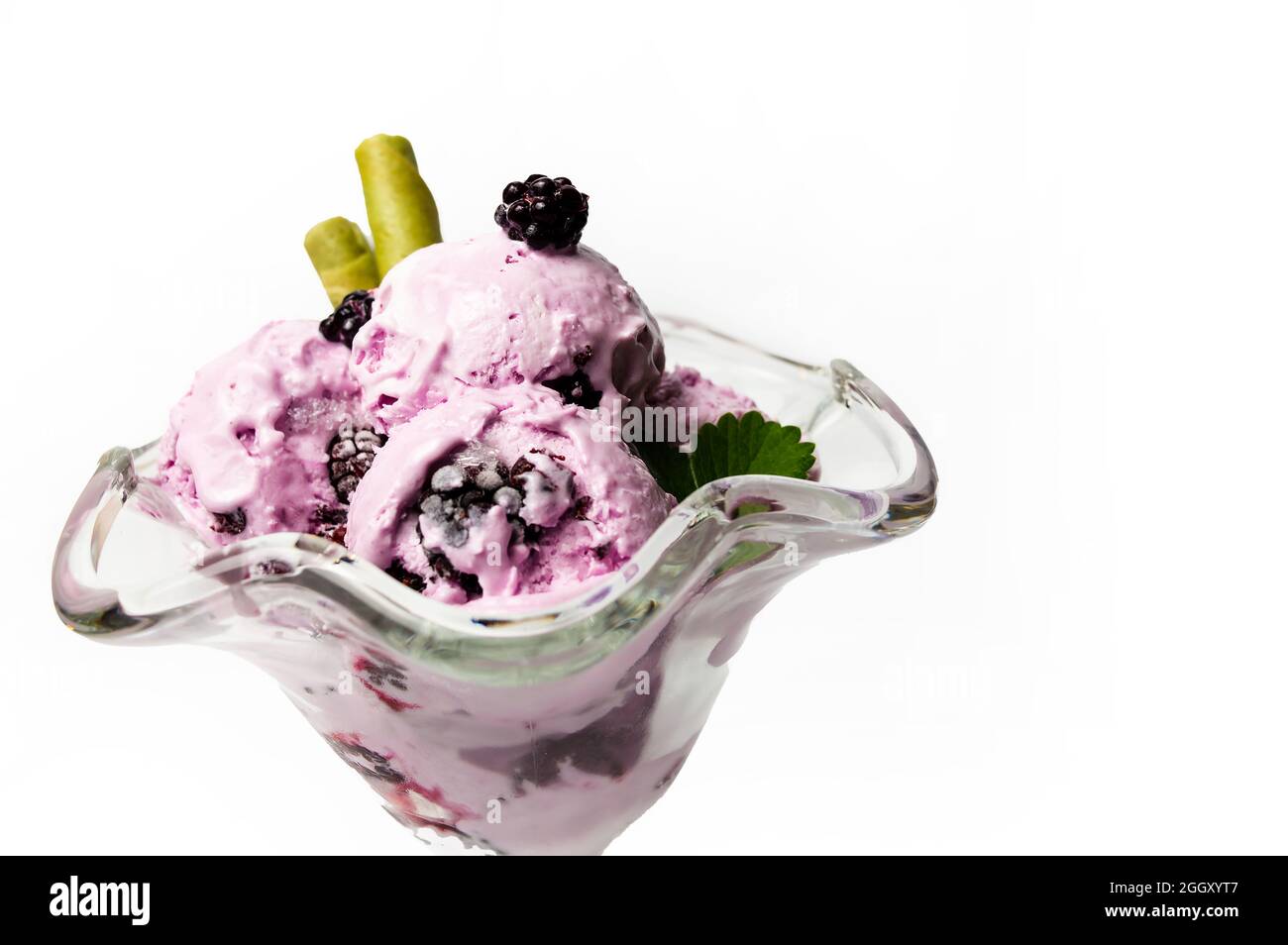 Crème glacée aux myrtilles avec fruits frais dans une tasse en verre avec un bâton de cachets isolé sur fond blanc Banque D'Images