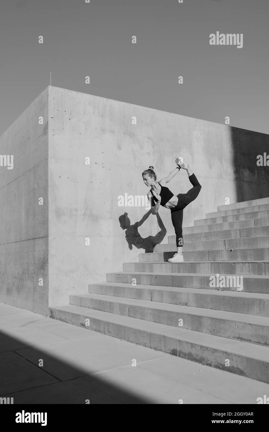 FIT jeune femme faisant yoga posture dans un environnement urbain en plein air noir et blanc Banque D'Images