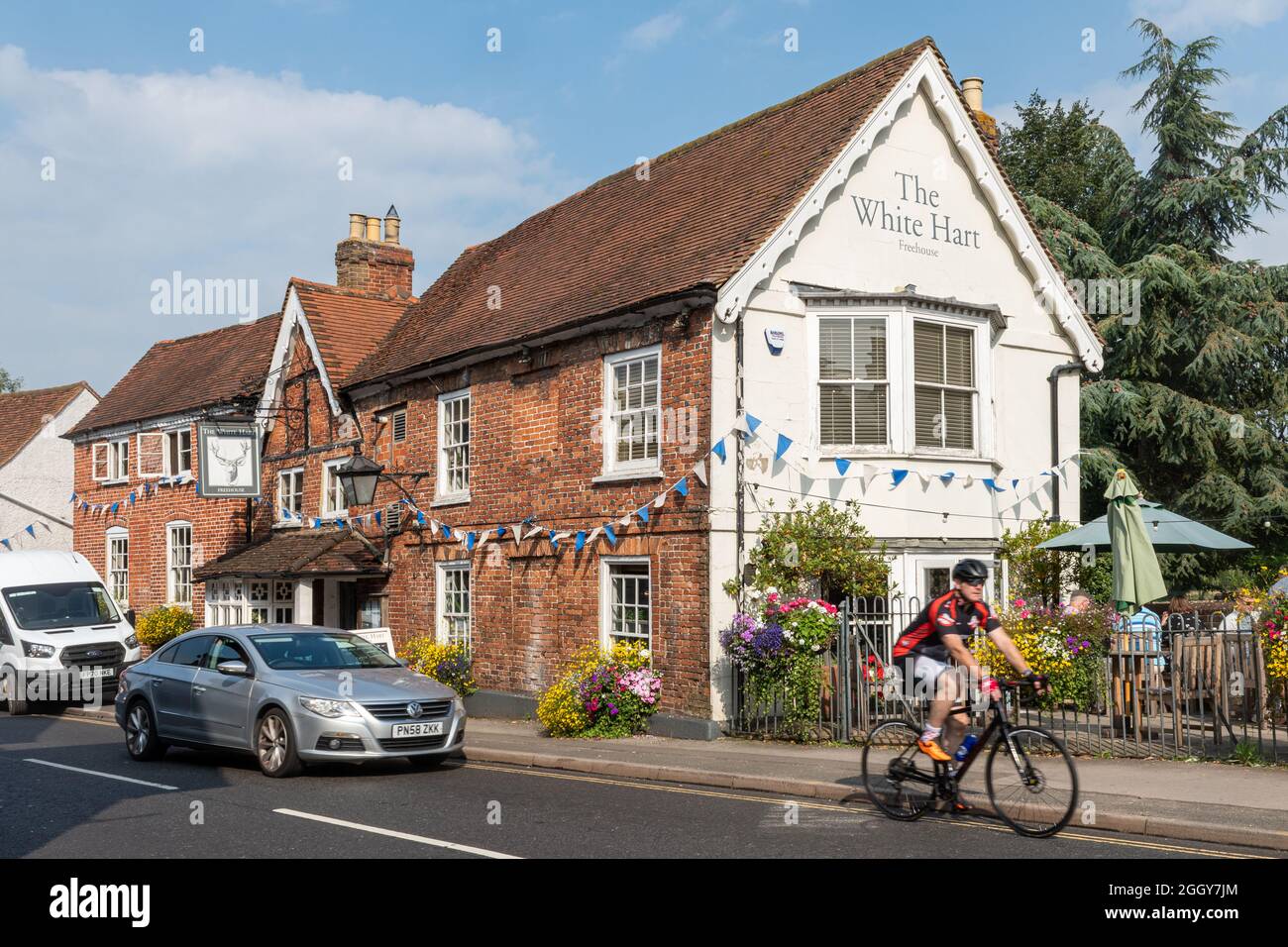 Le pub White Hart sur High Street dans le village de Chobham, Surrey, Angleterre, Royaume-Uni, en été avec un cycliste et de la circulation Banque D'Images