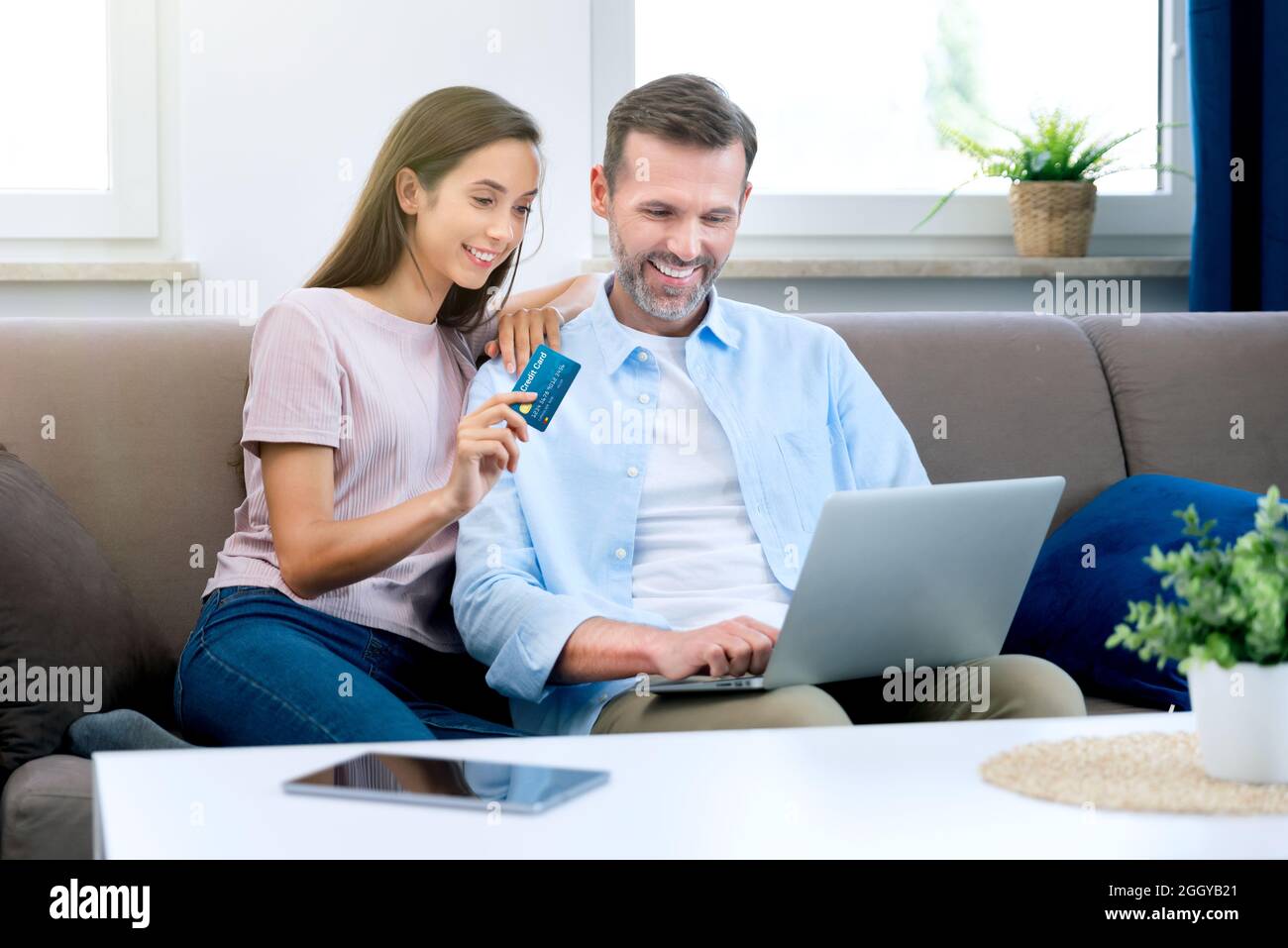 Couple heureux e-shopping sur Internet. Femme utilisant une carte de crédit, homme avec un ordinateur portable Banque D'Images