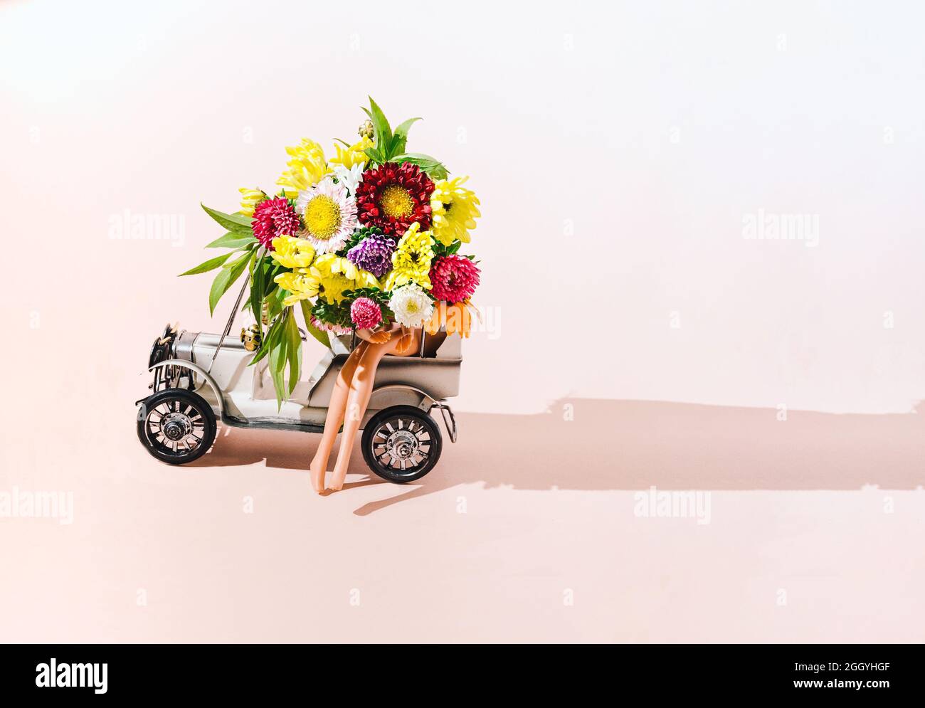 Une femme assise dans un vieux chrono avec un bouquet de différentes belles fleurs. Les jambes nues sont uniquement visibles. Mariage ou autre concept d'occasion spéciale Banque D'Images