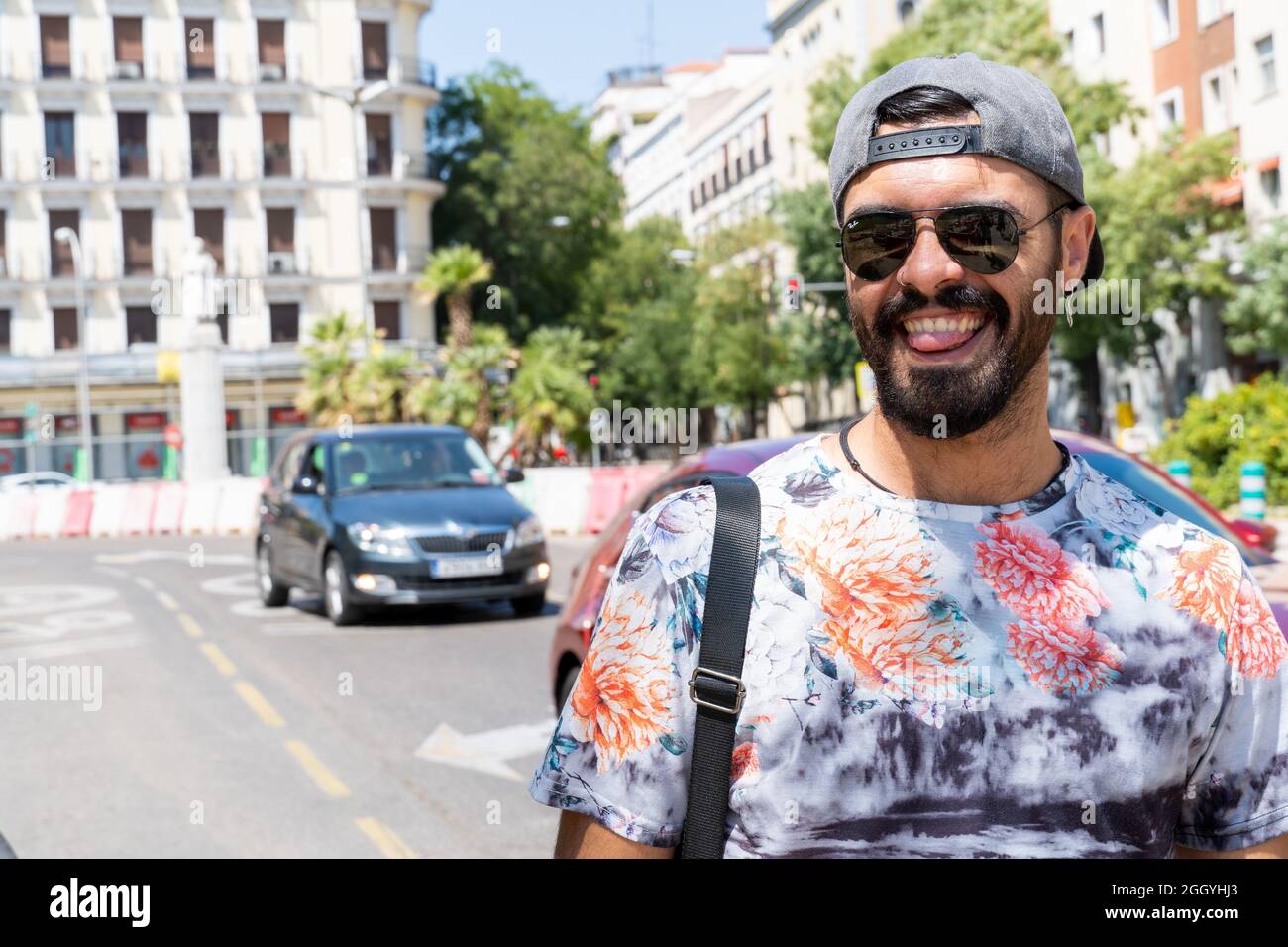 Un jeune homme dans une casquette arrière tirée et des lunettes de soleil  souriant dans la rue Photo Stock - Alamy