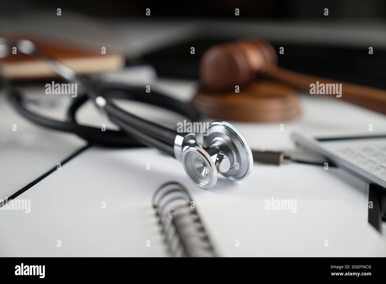 Concept de droit médical.Un Gavel, un carnet et un stéthoscope sur la table en verre.Lumière bleue. Banque D'Images