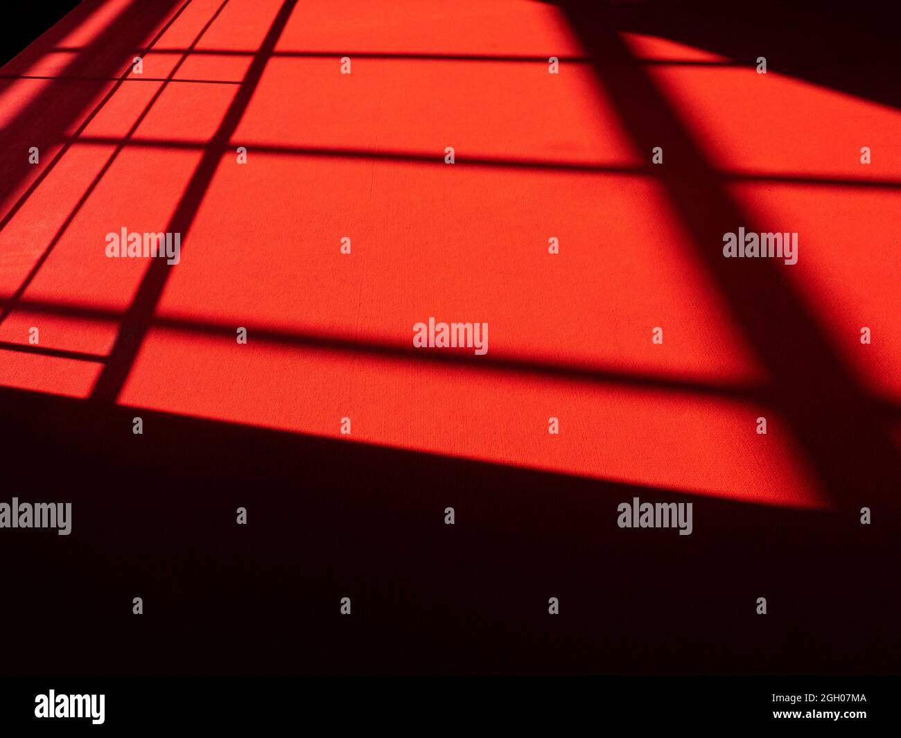 Tapis rouge avec lignes abstraites à la surface, lumière du soleil sur tapis rouge, silhouettes et ombres sur le sol Banque D'Images