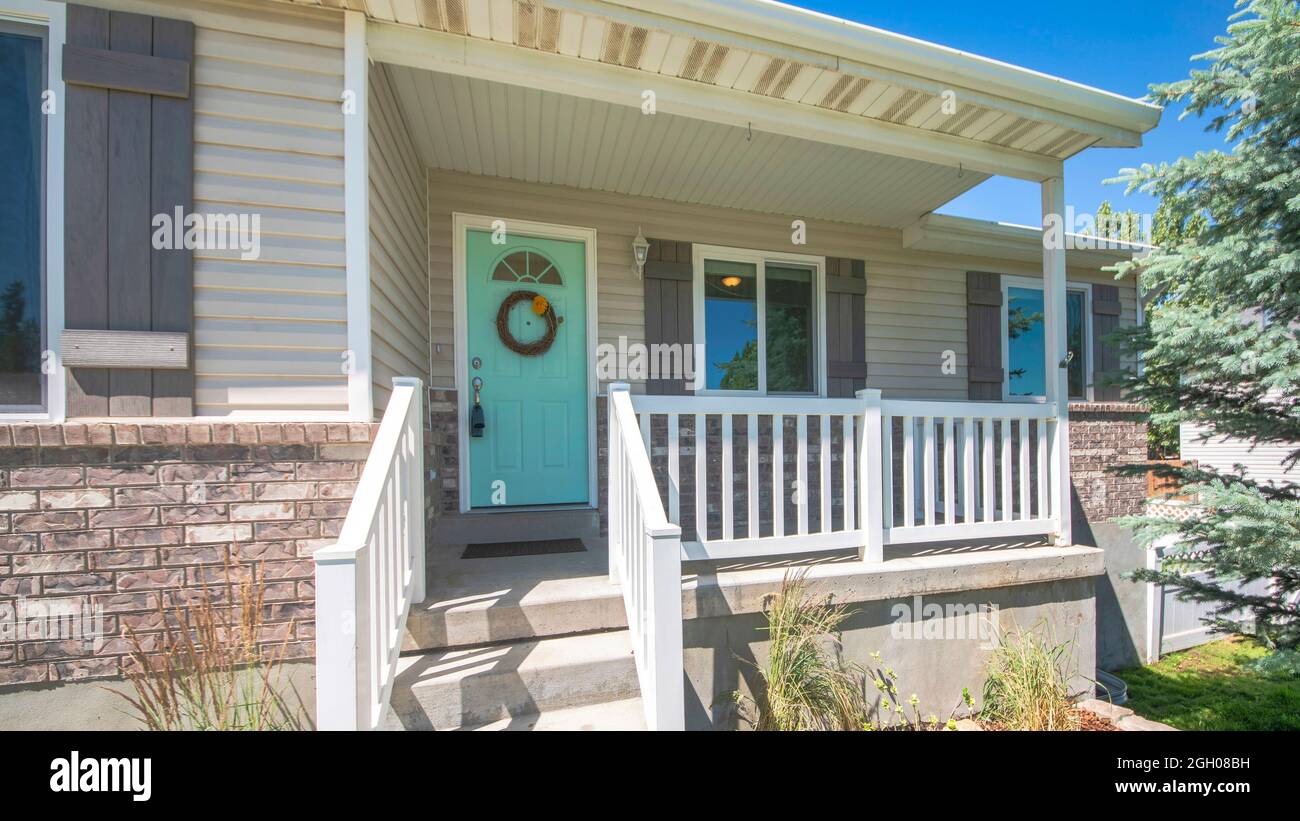 Pano extérieur d'une maison avec des briques, porche surélevé et fenêtres à double vitrage Banque D'Images