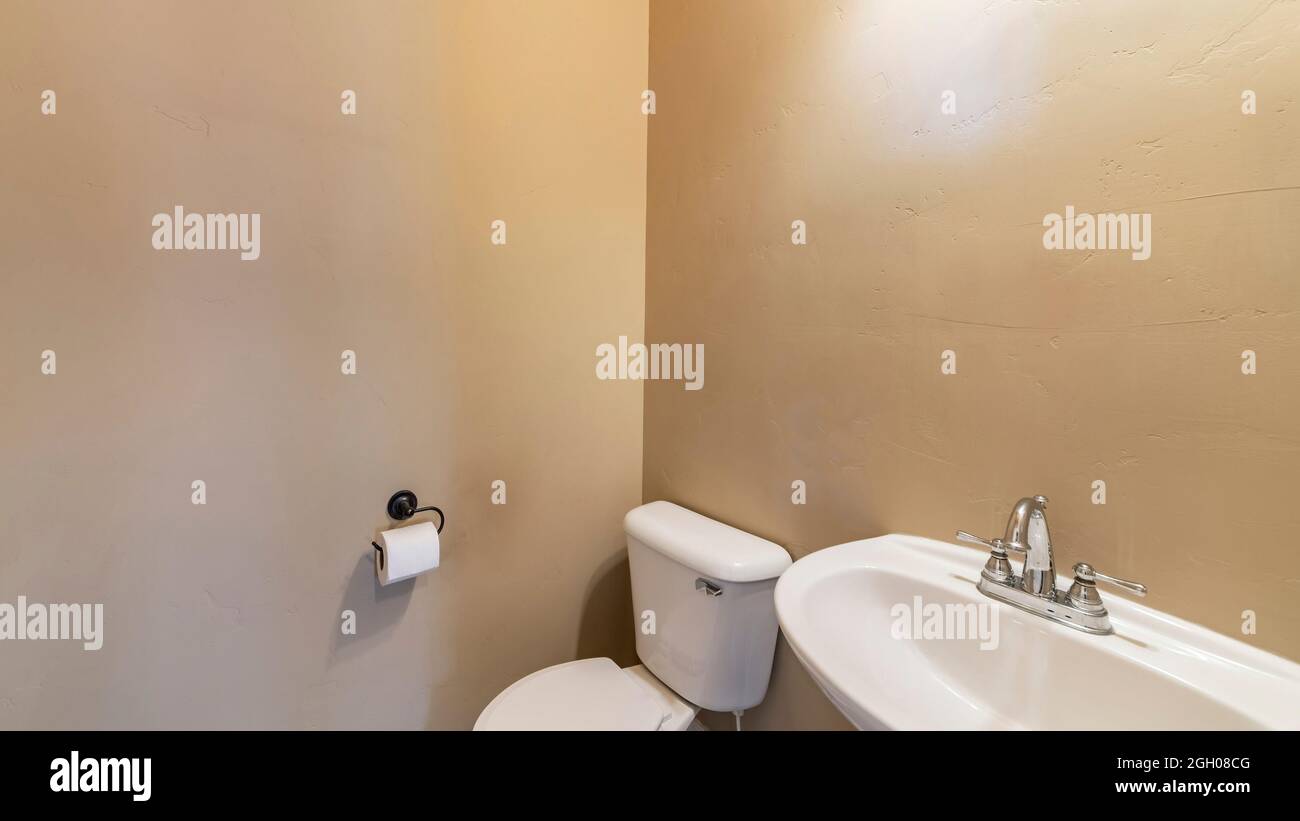 Salle de poudre Pano avec murs de couleur ocre, cuvette de toilette et évier Banque D'Images
