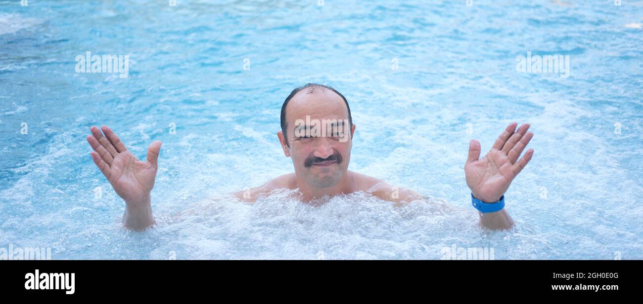 Homme asiatique mature dans une piscine thermale extérieure avec hydromassage. Banque D'Images