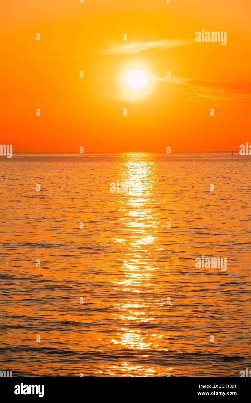 Soleil se couche sur l'horizon au coucher du soleil lever du soleil au-dessus  de la mer ou l'océan. Mer calme, les vagues de l'océan. Ciel naturel des  couleurs chaudes Photo Stock -