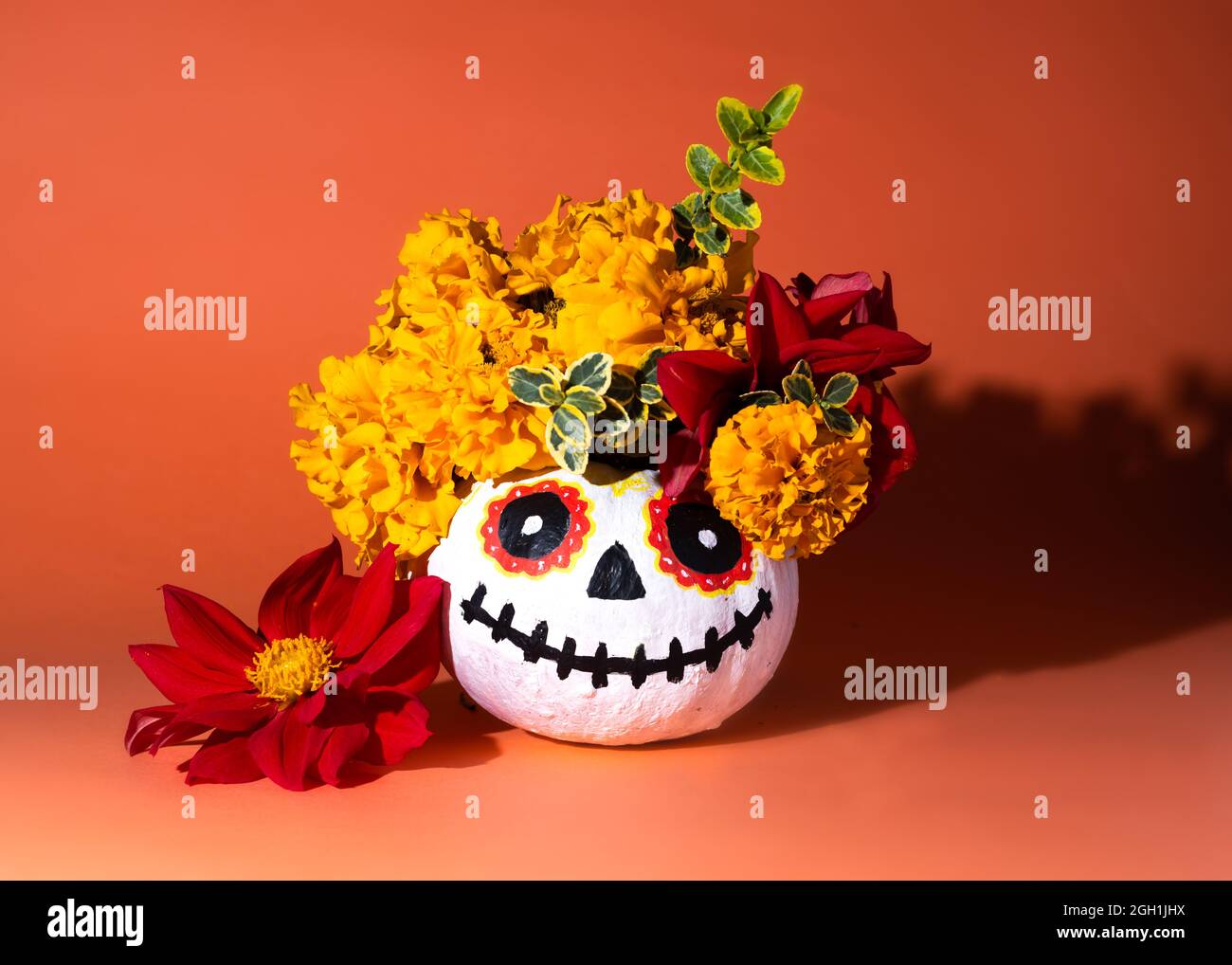 Citrouille d'Halloween peinte en blanc avec yeux dessinés. Décorée avec une couronne de marigolds et de dahlias. Célébration du jour des morts - Dia de los Muerto Banque D'Images
