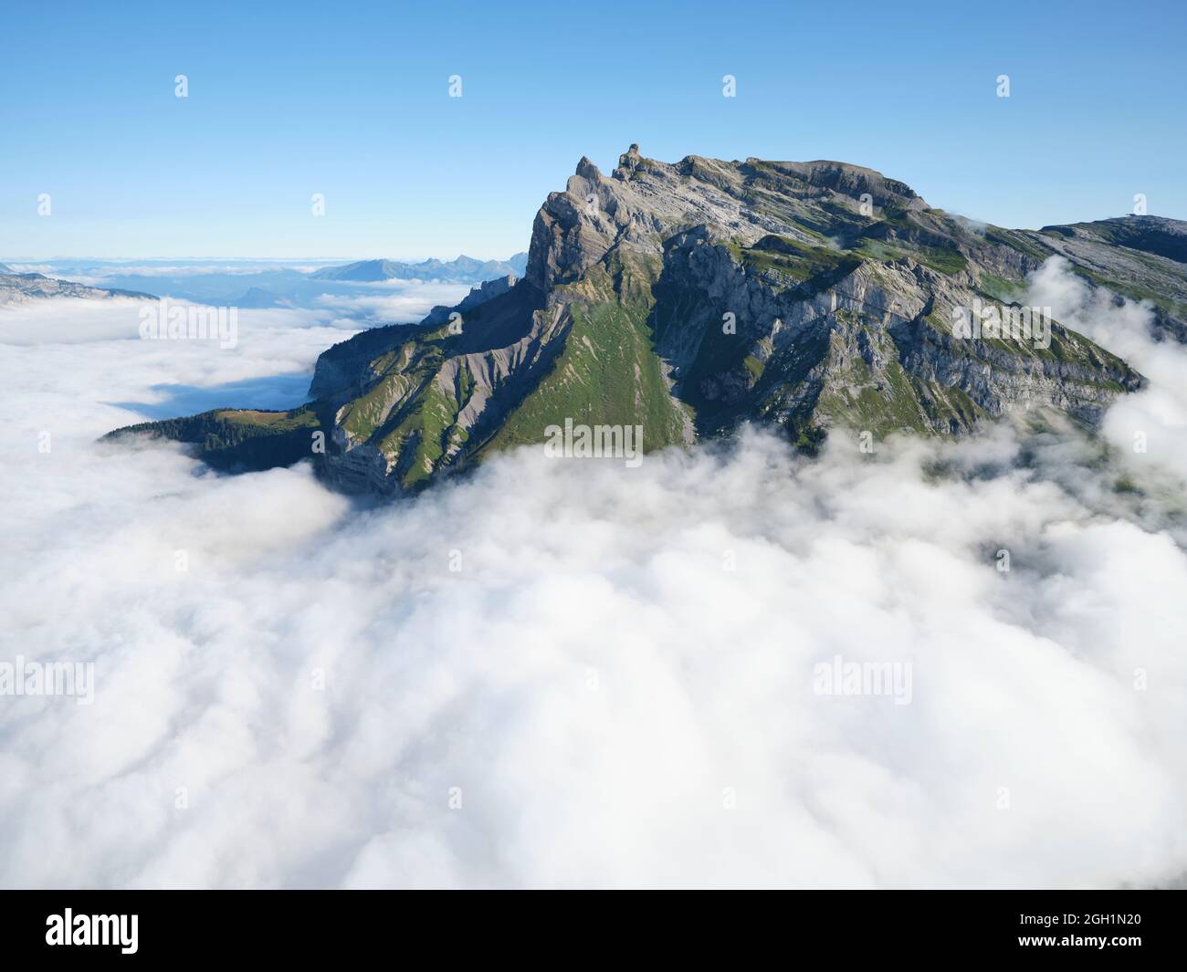 VUE AÉRIENNE. Aiguille de Varan (altitude : 2544m) entourée de nuages de basse altitude le matin. Passy, haute-Savoie, France. Banque D'Images
