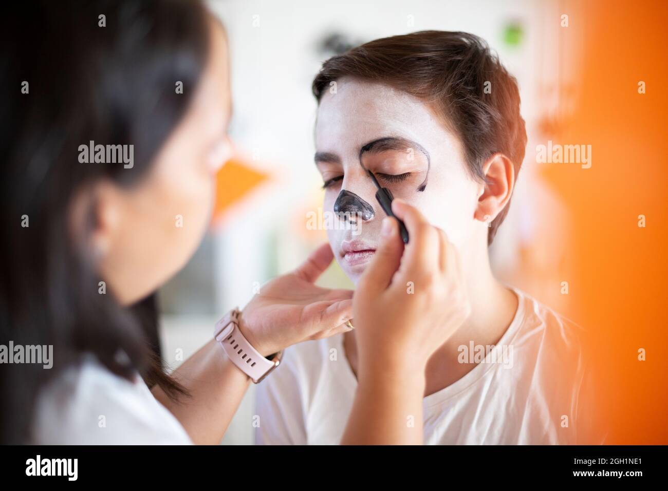 Gros plan sur une femme qui met du maquillage sur un adolescent pour la célébration du jour des morts. (Dia de los Muertos). Banque D'Images