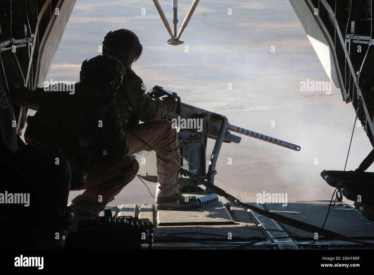 Caporal du corps des Marines des États-Unis Zachary Hughes (premier plan), instructeur de tactique d'armement, Escadron d'hélicoptères lourds maritimes 363, observe le Cpl lance. Madison DeLoach exploite une mitrailleuse de calibre 50, dans la vallée de la rivière Helmand, province de Helmand, Afghanistan, le 5 janvier, 2011. DeLoach a actionné la mitrailleuse de calibre .50 pendant les opérations de vol avec la direction de Hughes. Banque D'Images