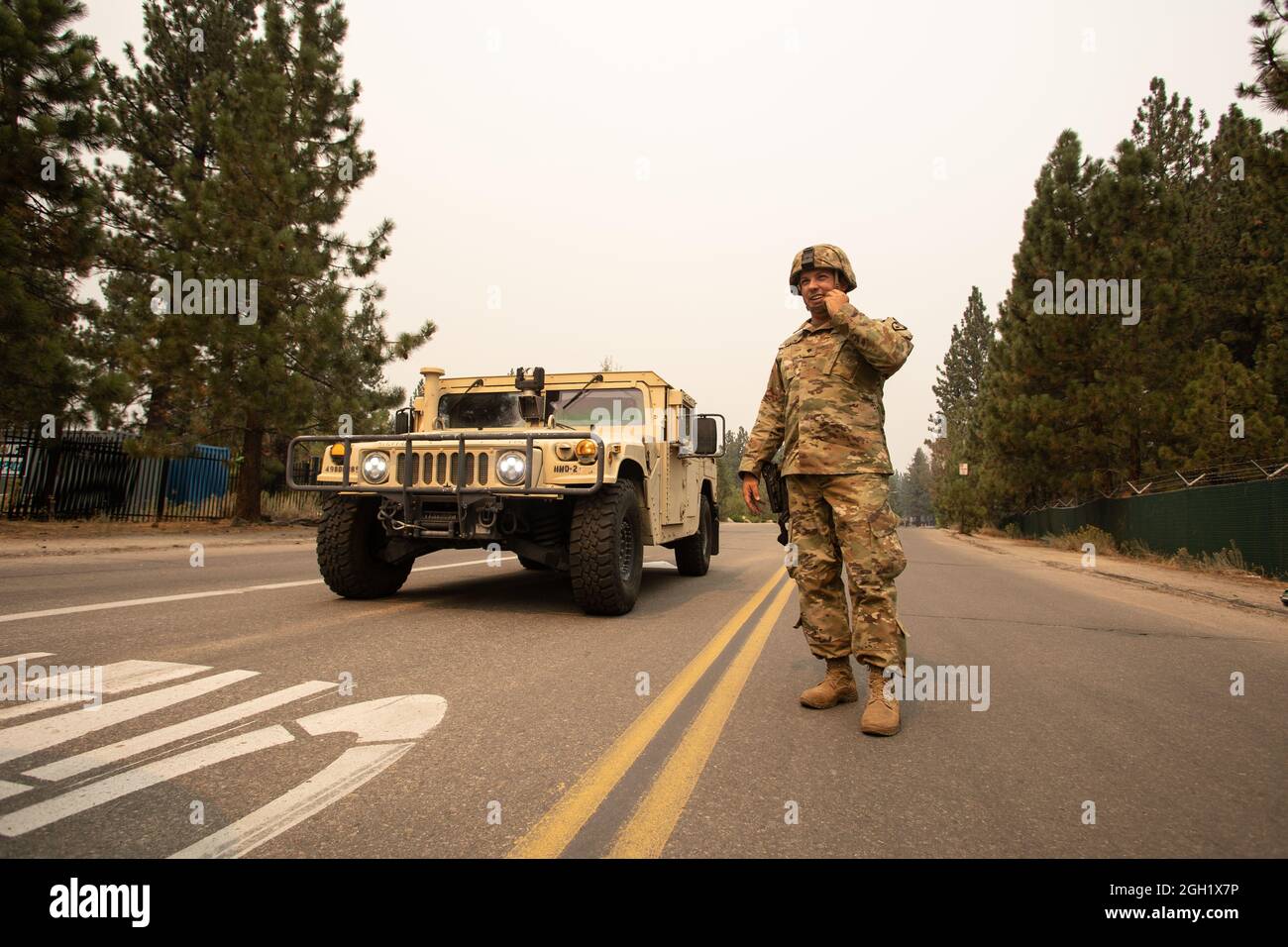 SPC de l'armée américaine. Dace Taylor, de la 270e compagnie de police militaire de la Garde nationale de Californie, ajuste la mentonnière de son casque tout en parlant à un autre soldat, le 1er septembre 2021, à South Lake Tahoe, en Californie, alors que le caldor Fire empiète sur la ville évacuée. CAL Guard a activé 150 policiers militaires le 30 août pour soutenir la patrouille routière de Californie avec des points de contrôle à des fermetures dures pendant que la zone est évacuée. (É.-U. Photo de la Garde nationale aérienne par le sergent d'état-major. Crystal Housman) Banque D'Images