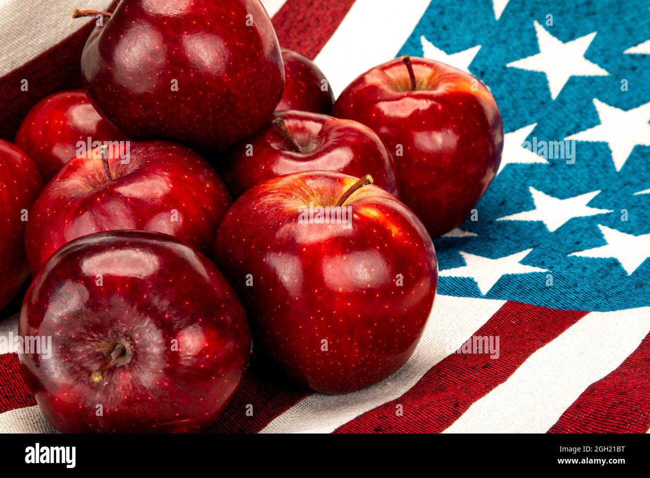 Pile de pommes rouges sur un tissu en coton avec des étoiles blanches sur fond bleu et des rayures rouges et blanches. Banque D'Images