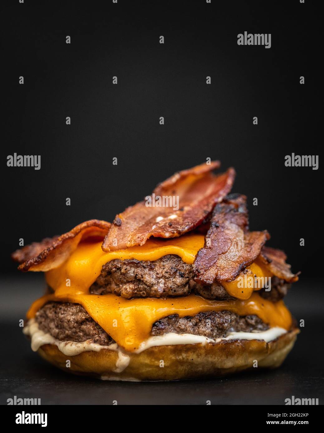 Gros plan d'un délicieux hamburger appétissant avec du bacon frit, du fromage fondu et du bœuf Banque D'Images