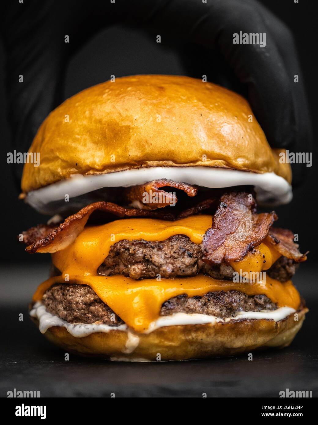 Gros plan d'un délicieux hamburger appétissant avec du bacon frit, du fromage fondu et du bœuf Banque D'Images