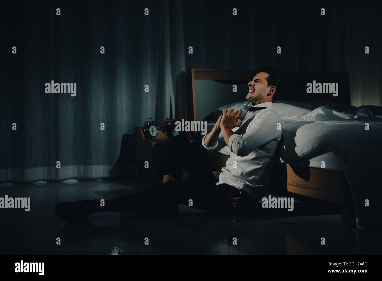 Un jeune homme en vêtements d'affaires décontractés tenant un pistolet près des yeux et de viser son menton pour se tuer ou commettre le suicide. Concept de désespoir et Banque D'Images