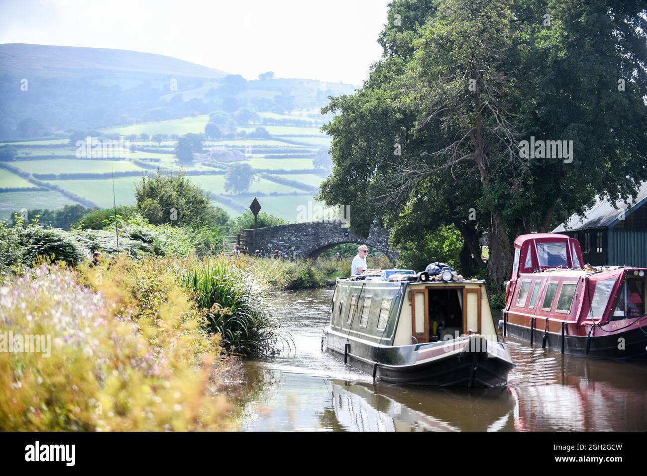 Une belle scène comme une barge voyage le long du Monbucshire et du canal de Brecon dans le sud du pays de Galles un beau samedi après-midi tandis que les gens apprécient le temps de la fin de l'été à travers le Royaume-Uni. Banque D'Images