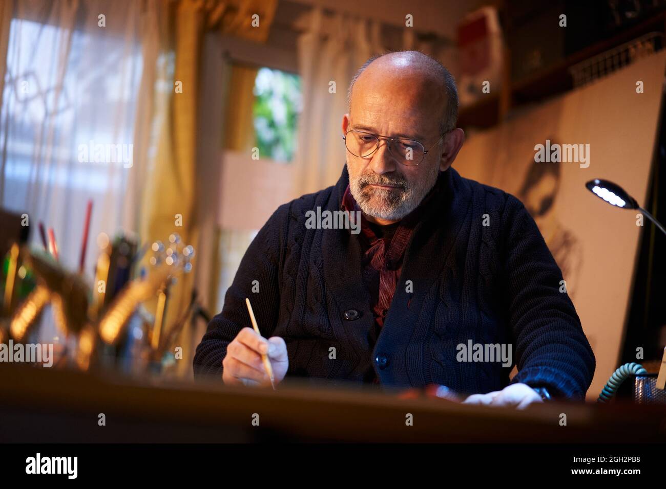 Artiste travaillant en studio. Homme d'âge moyen qui fait des œuvres d'art créatives, peint en aquarelle avec un pinceau. Banque D'Images