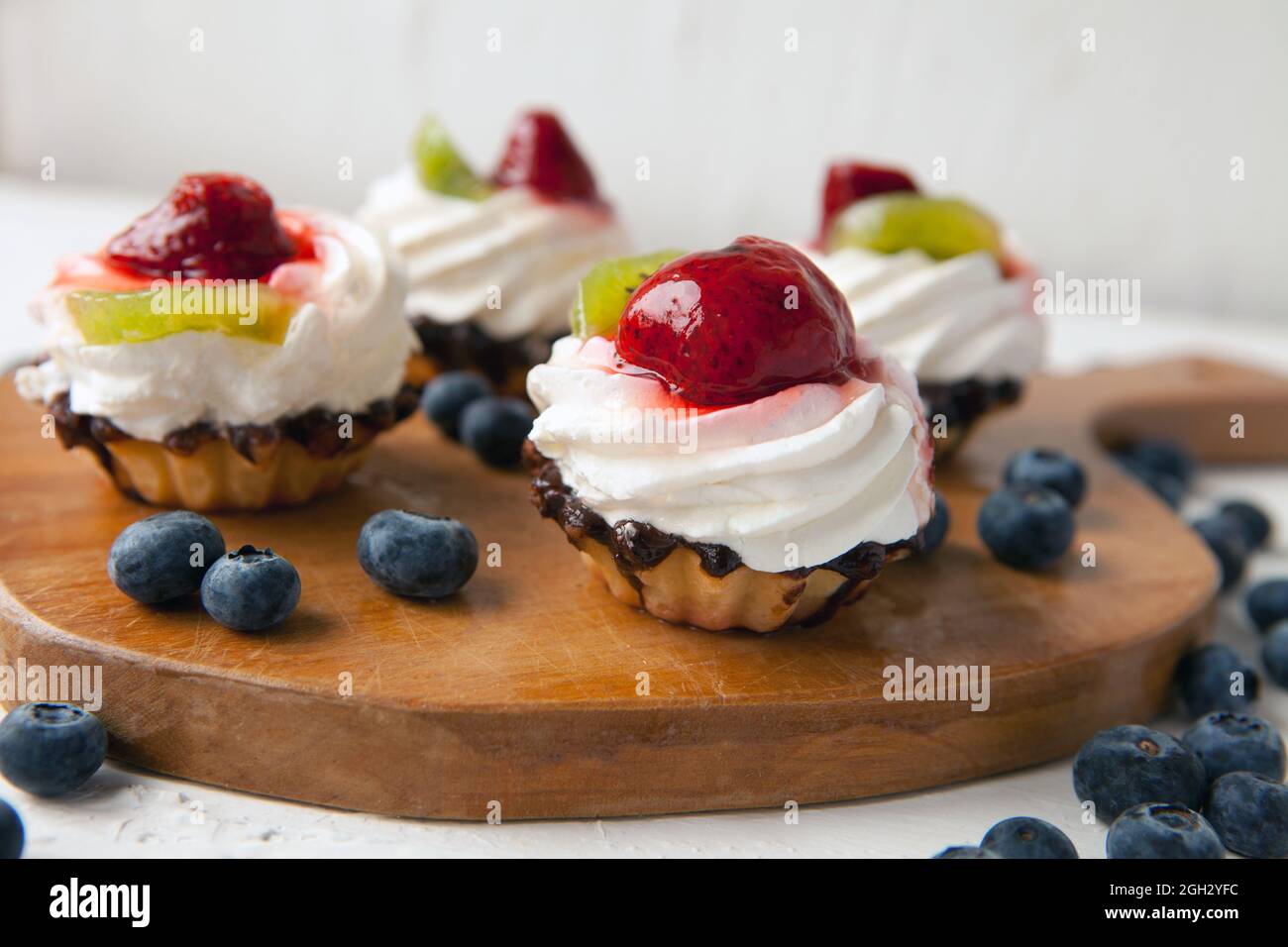 petits gâteaux avec fromage cottage sur plateau millésime-délicieux muffin avec fraise et kiwi sur assiette en bois Banque D'Images