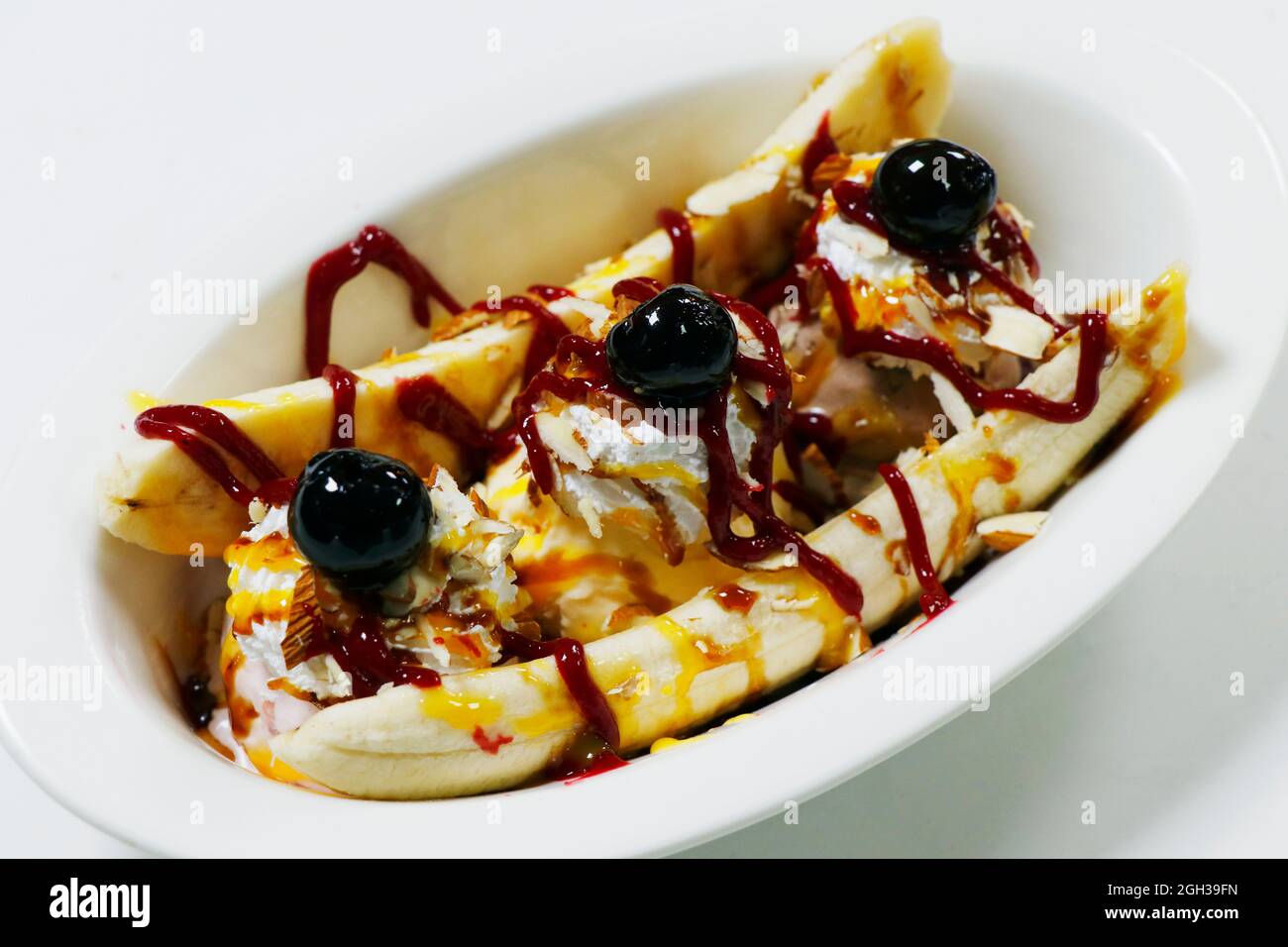 la banane est coupée avec des crèmes glacées, des cerises et de la sauce caramel à la framboise Banque D'Images