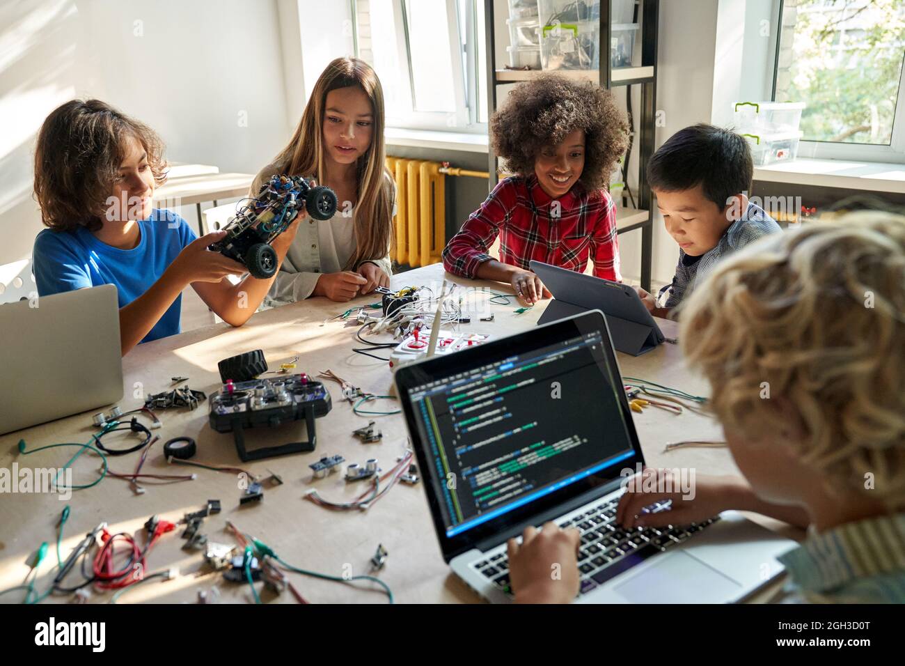 Divers élèves des écoles construisent des voitures robotisées à l'aide d'ordinateurs et de codage. Banque D'Images