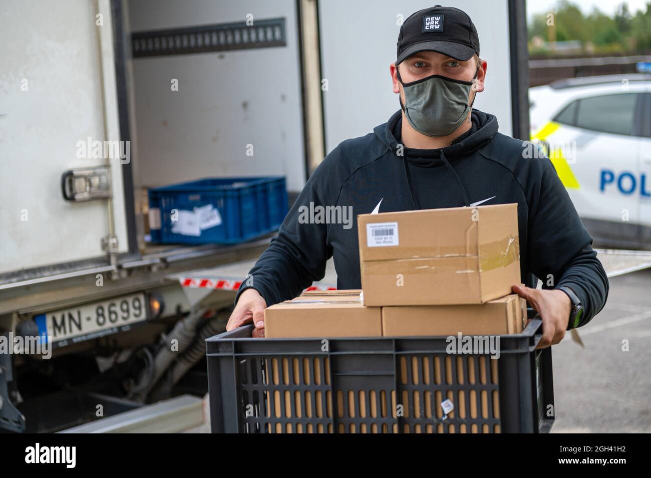 Riga, Lettonie - 3 septembre 2021 : un homme avec un masque décharge les boîtes d'un camion, livraison de marchandises Banque D'Images