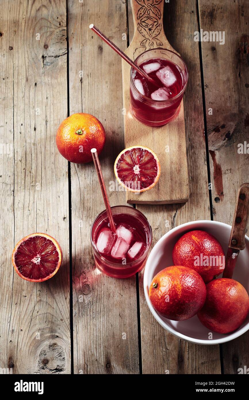 Cocktail d'orange de sang rouge, boisson aux agrumes avec glaçons sur fond de bois. Banque D'Images