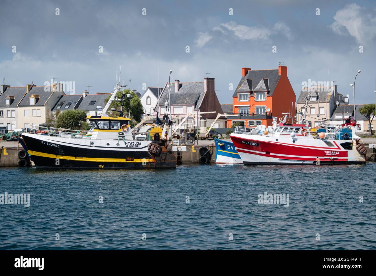 Le Guilvinec (France), 07 août 2021. Chalutiers dans le port avec les maisons colorées du village. Banque D'Images