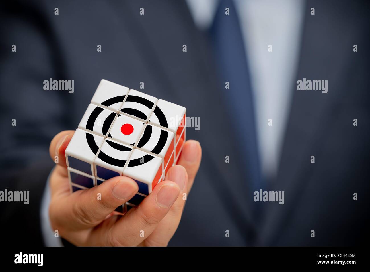 Mains d'un homme d'affaires tenant un cube avec une icône d'objectif d'affaires visible. Banque D'Images