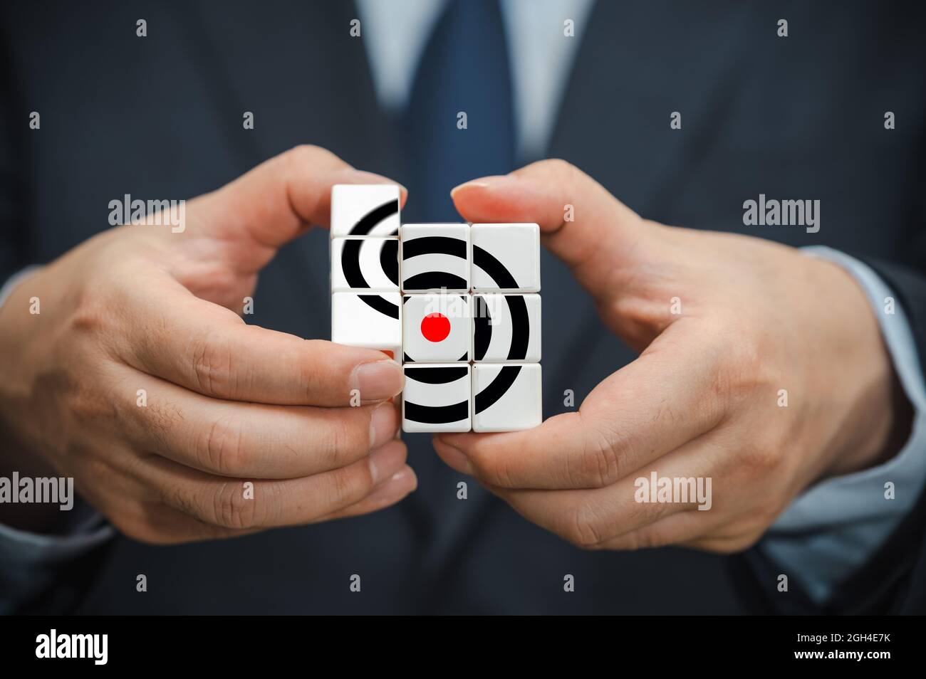 Mains d'un homme d'affaires tenant un cube avec une icône d'objectif d'affaires visible. Banque D'Images