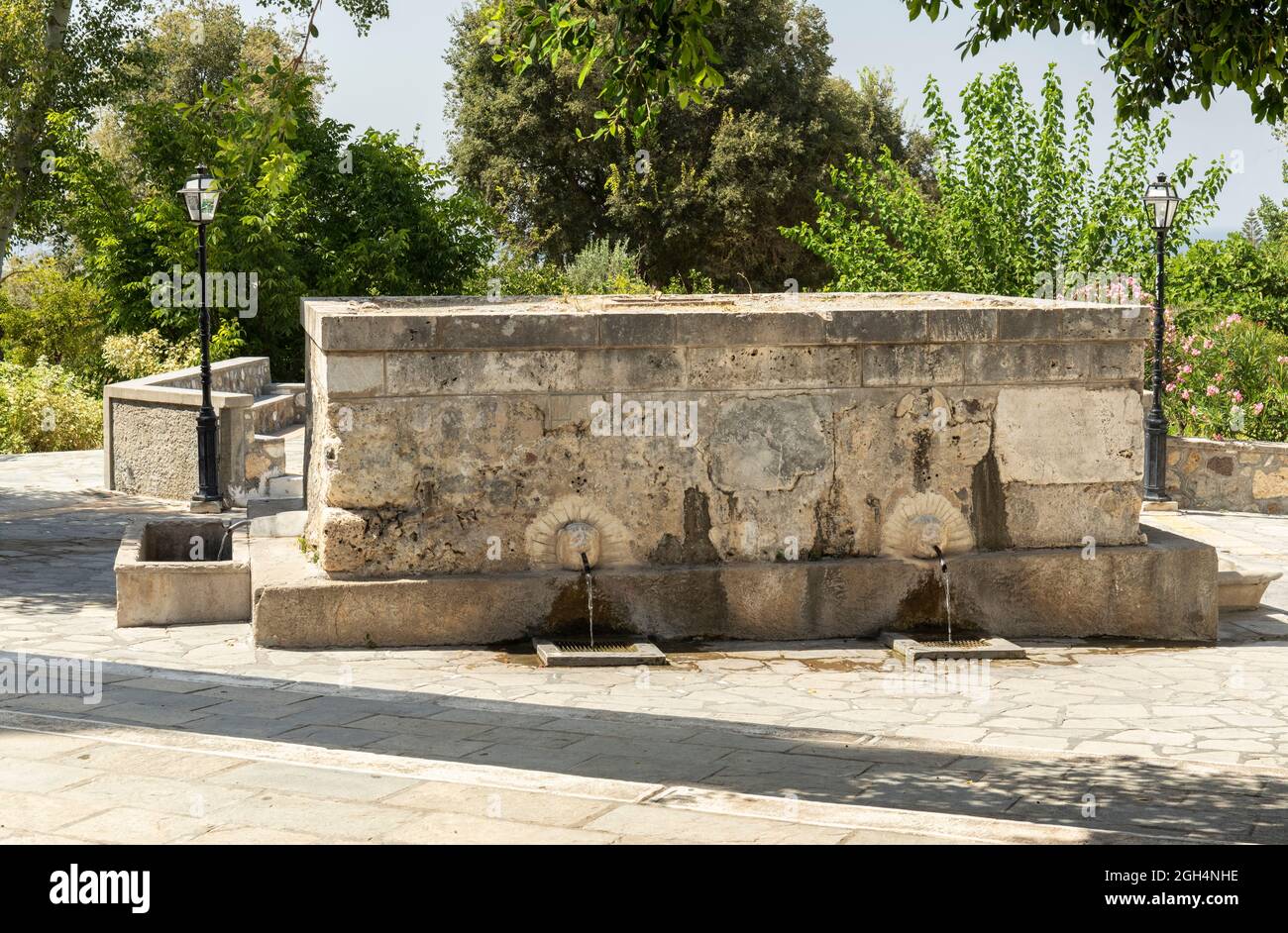 Abonnés la fontaine Pyli Spring avec 6 sculptures gargouille d'une tête de lions qui jaillissent de l'eau de source à travers une buse. Village de Pyli, Kos, Grèce. Banque D'Images