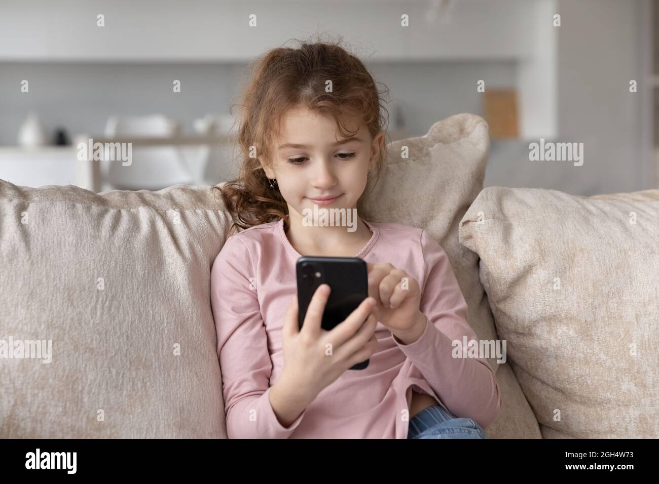 Bonne petite fille adorable fille adorable en utilisant le téléphone portable. Banque D'Images