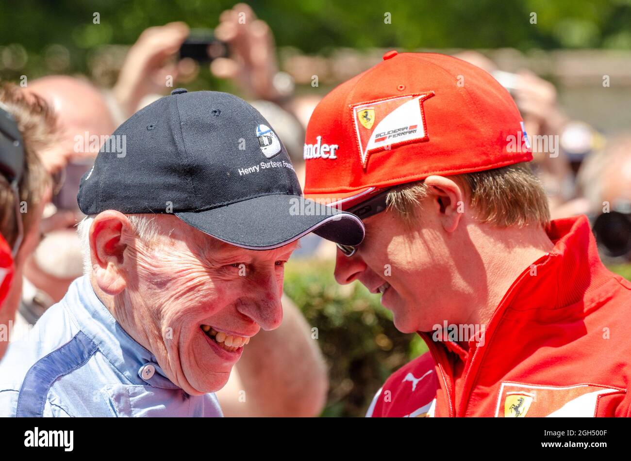 John Surtees pilote vétéran des blagues avec les pilote de Formule 1 Kimi Raikkonen. Jeunes et vieux pilotes parler dans des fosses à Goodwood Festival Banque D'Images