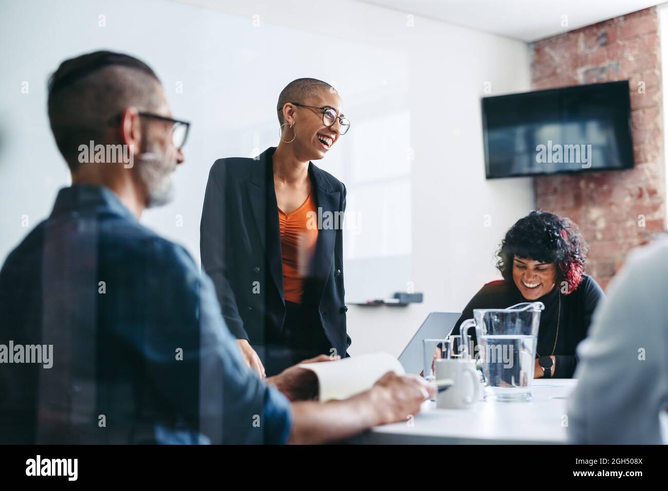 hommes d'affaires riant lors d'un briefing dans un bureau. Groupe de gens d'affaires prospères assistant à leur réunion du matin dans un lieu de travail moderne. CREA Banque D'Images