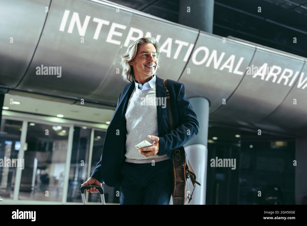 Homme d'affaires marchant dans un terminal d'aéroport international. Homme voyageur avec valise à l'aéroport. Banque D'Images