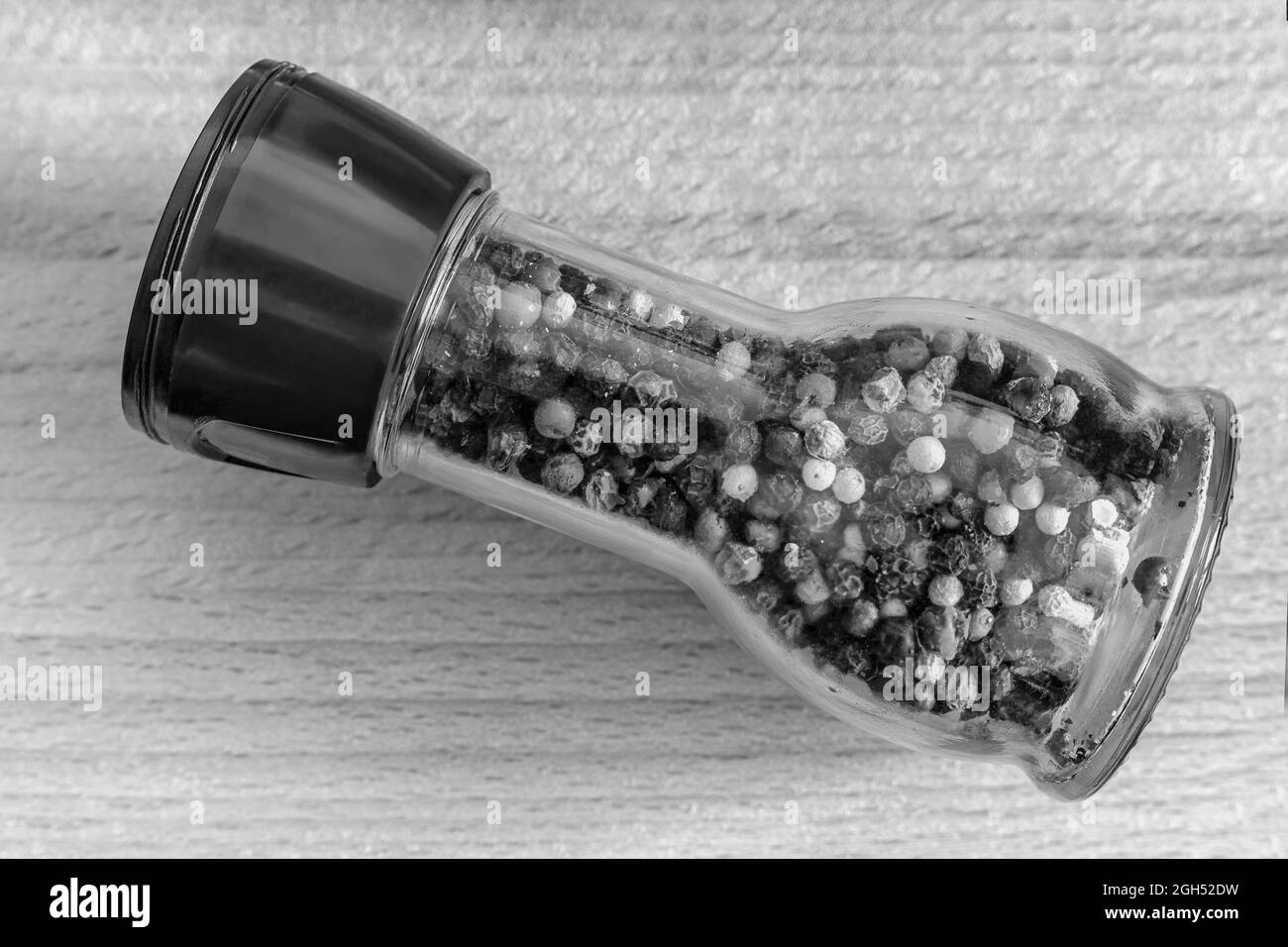 Un ensemble d'épices : pois noir, blanc, poivron rouge dans une bouteille de verre sur une table en bois. Vue de face, espace de copie Banque D'Images
