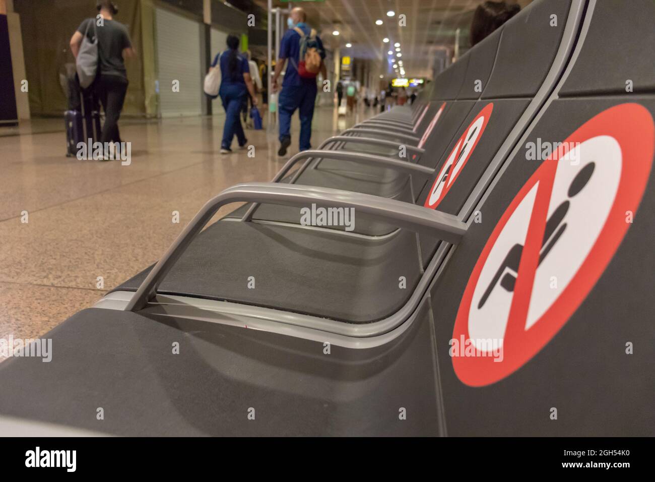 BARCELONE, ESPAGNE - AOÛT 18,2021 : rangée de sièges dans le terminal de départ de l'aéroport de Barcelone sans siège et avec les panneaux de distance Banque D'Images