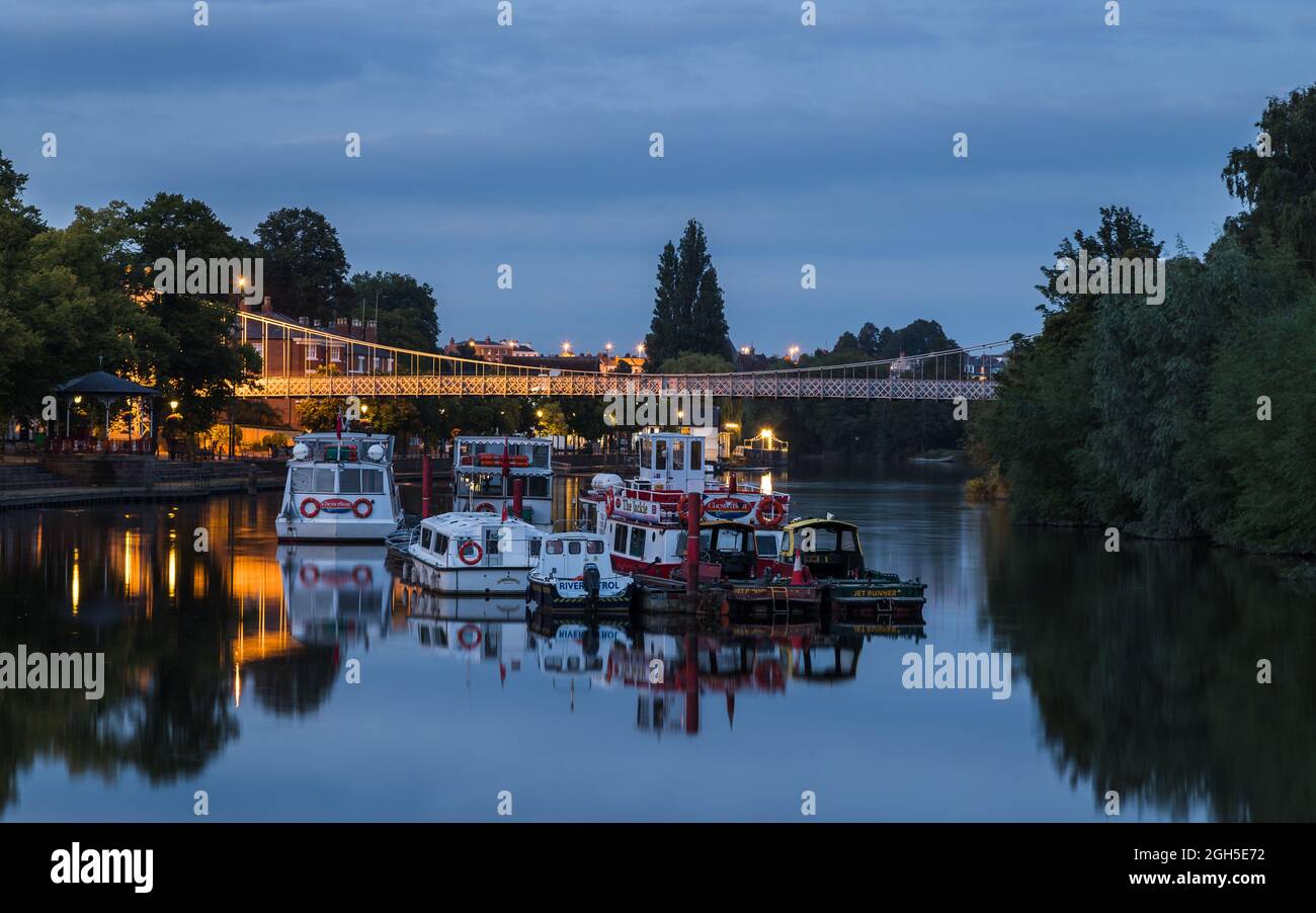 Divers bateaux, dont des croiseurs de rivière amarrés au crépuscule sur la rivière Dee à Chester, sous le pont Queens Park en septembre 2021. Banque D'Images