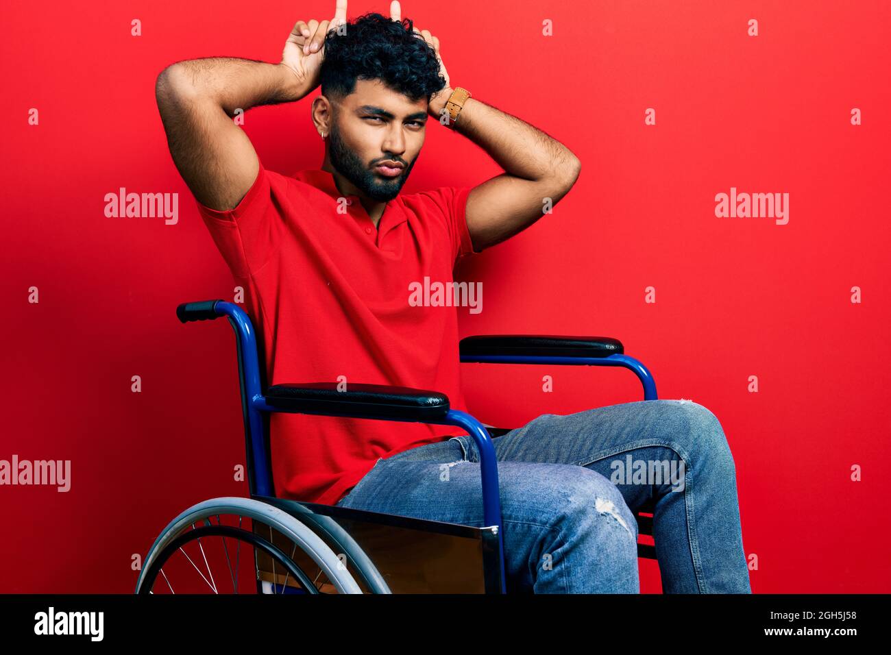 Homme arabe avec barbe assis sur un fauteuil roulant faisant un geste drôle  avec le doigt sur la tête comme cornes de taureau Photo Stock - Alamy