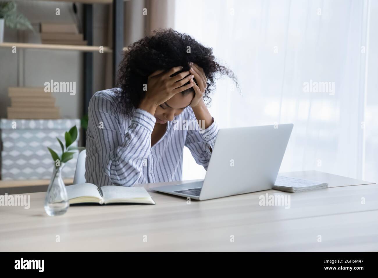 Une femme noire en colère s'assoit à la tête de la hug sur le lieu de travail Banque D'Images