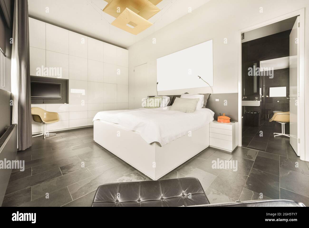 Chambre spacieuse et lumineuse avec lit Queen Size et salle de bains attenante dans un appartement moderne de style loft avec murs blancs et sol en marbre Banque D'Images