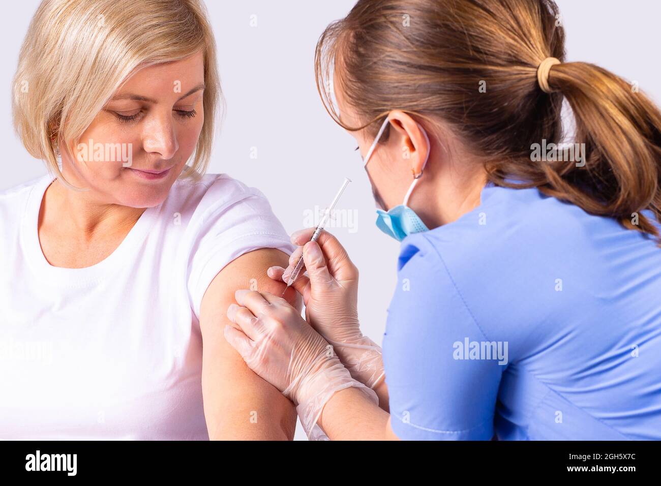 Photo en gros plan d'une femme médecin portant un masque médical et des gants mettant le vaccin sur une patiente contre le coronavirus. Banque D'Images