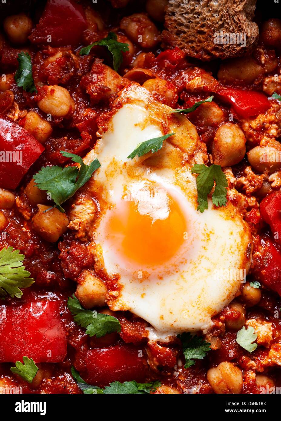 Vue de dessus de chakchouka avec côté ensoleillé vers le haut de l'oeuf dans une délicieuse sauce tomate avec morceau de pain de seigle dans le bol Banque D'Images