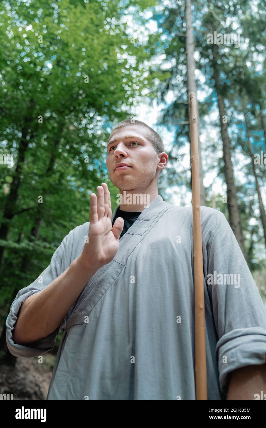 Angle bas de l'homme avec le bâton tenant la main près de la poitrine tout  en pratiquant le kung fu dans les bois Photo Stock - Alamy
