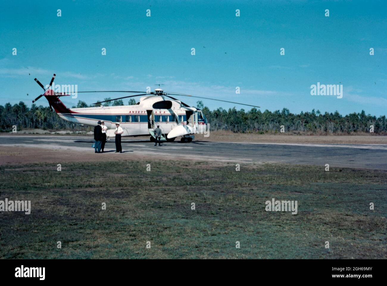 Un hélicoptère Sikorsky d'Ansett ANA au sol dans le Queensland, en Australie, en 1965. Il a été numéroté VH-BRI et nommé 'Golden Islander'. Il a été utilisé sur un service de passagers de Proserpine à Hayman Island qui a commencé en 1965. Ansett Australia a été fondée par Reginald «Reg» Ansett en 1935, alors qu'Ansett Airways Pty Ltd. En 1957 Ansett Airways a acheté Australian National Airways (ANA). À partir de 1981, il a été connu sous le nom d'Ansett et en 1990 est finalement devenu Ansett Australia. Cette image provient d'un ancien transparent couleur Kodak amateur, une photographie vintage des années 1960. Banque D'Images