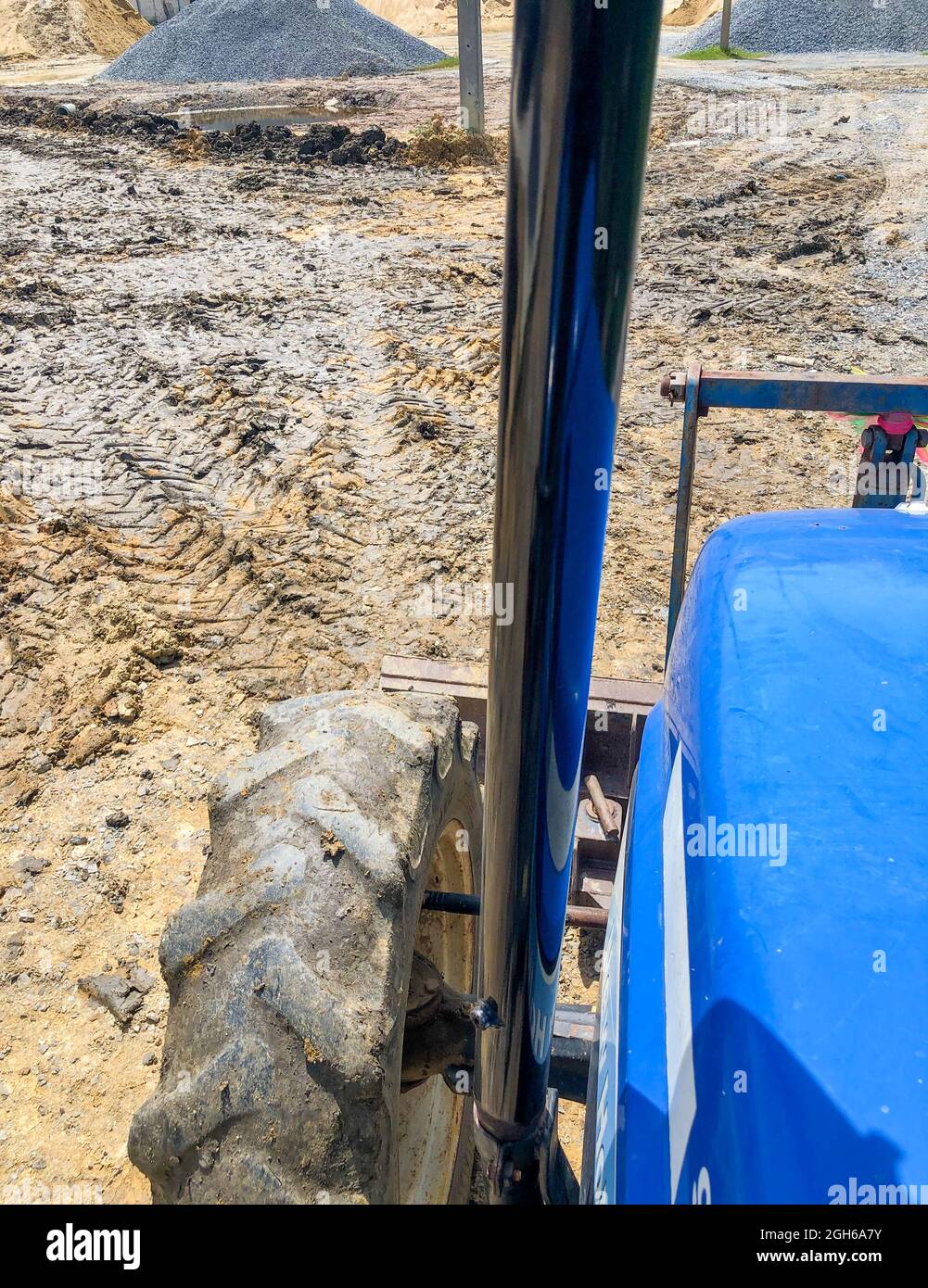 Le tracteur règle le sol avec le bouteur avant, vitesse lente, au-dessus de la roue avant gauche. Banque D'Images