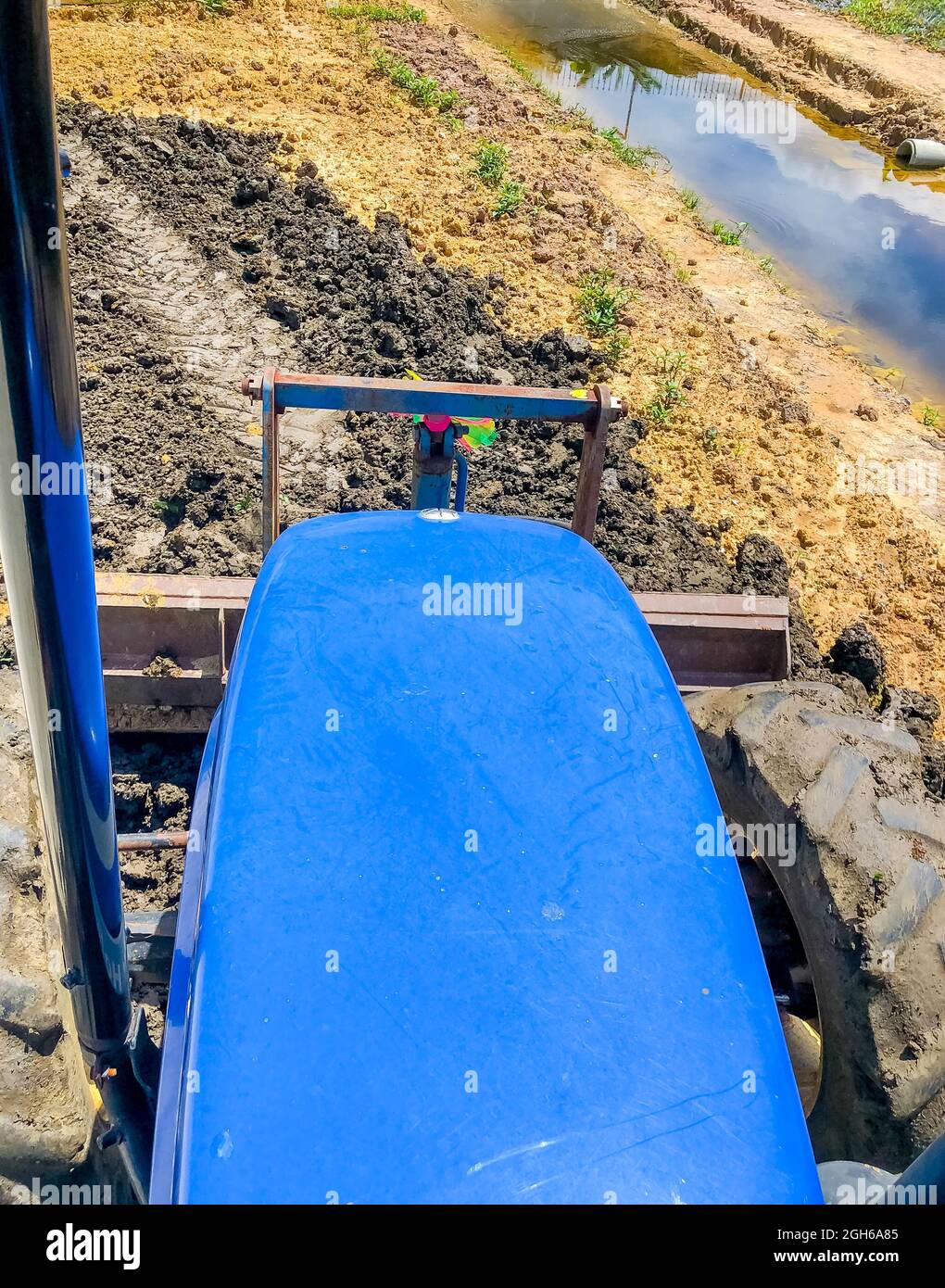 Le tracteur règle le sol à l'aide d'un bouteur avant, à vitesse lente, au-dessus de la roue avant gauche. Bien tailler le bassin. Banque D'Images